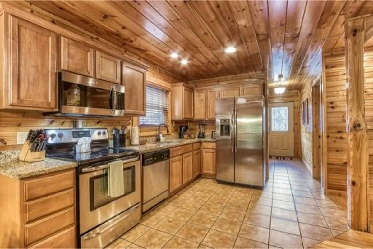A cozy and functional kitchen space boasting stainless steel appliances, granite countertops, and wooden cabinetry. The layout is perfect for meal preparation and family gatherings, with a welcoming ambiance that blends luxury with comfort.