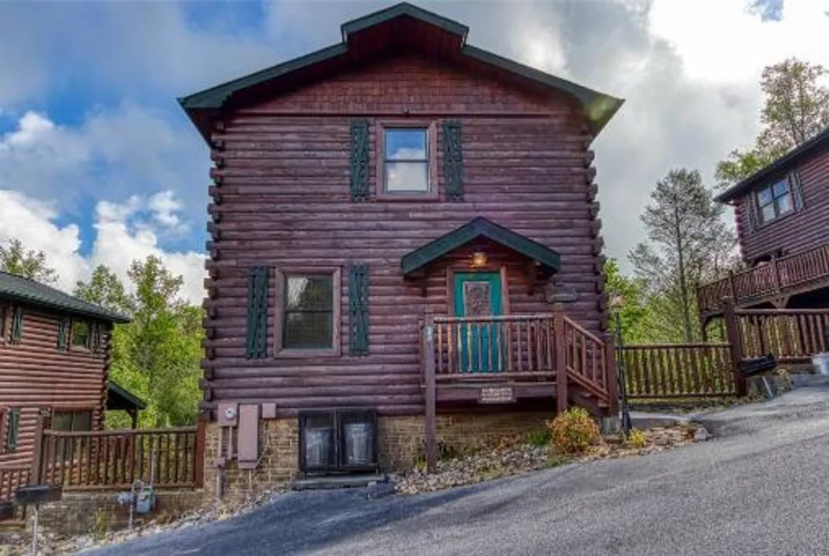 An exterior view of the cabin showcasing its classic log architecture, green shutters, and a welcoming wooden porch—an ideal spot for relaxing after a day of adventure. The scene is bathed in cozy, golden-hour lighting, inviting families to gather.